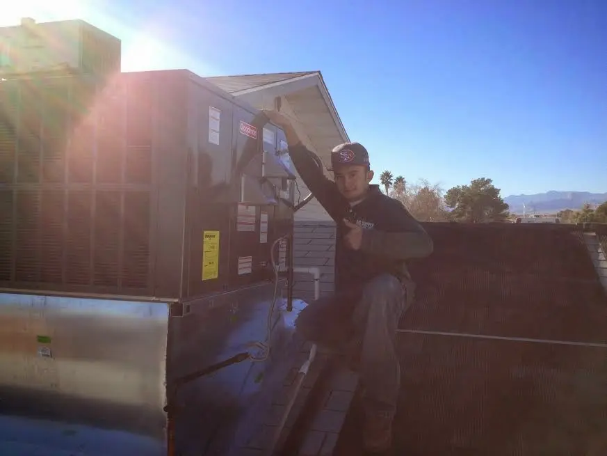 HVAC technician performing Air Duct Repair on a rooftop unit in Garden Home-Whitford